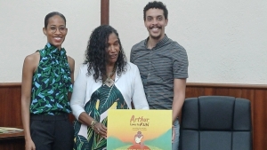 Daughter of Arthur Wint and author of &quot;Arthur Loves to Run,&quot; Colleen Wint-Bond (middle) displays the cover of the book alongside her daughter, Djavila Ho (left) and illustrator for the book, Patrick Meikle (right).