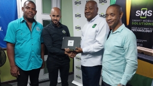 JFF president Michael Ricketts (second right) and general secretary Dennis Chung (right) accepts one of five laptops from Dane Spencer, managing director of SMS, while AWDS&#039; CEO Mark Anthony Bernard looks on.