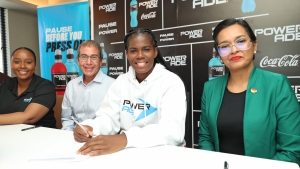 Bunny Shaw signs while Chantelle McDonald, (Brand Manager, Powerade), Andrew Mahfood (CEO, Wisynco) &amp; Nadine Gosine, (Caribbean Marketing Manager, The Coca Cola Company) look on.