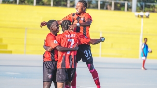 Arnett Gardens players celebrate one of their many goals.