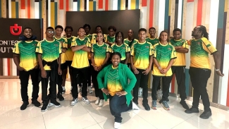 Team manager Lloye Guwalani (kneeling) share a photo opportunity with members of the delegation at the Sangster International Airport on Tuesday.