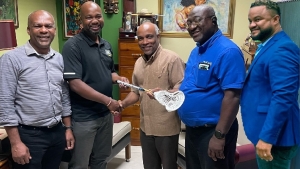 Jamaica Lacrosse Association President Carl  Hutchinson (second left) presenting JOA President Christopher Samuda with a crosse bearing the signatures of Jamaica&#039;s players. Sharing in the moments are JOA CEO Ryan Foster (r) and JLA directors Elvis Jenkins and Dwight Clarke.
