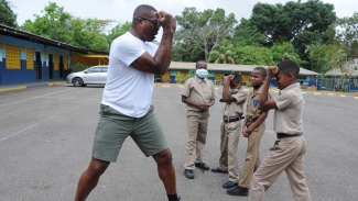 Students of Good Hope Primary School in St Catherine give their full attention to Ruddock as he demonstrates the fundamentals of boxing while on a recent visit to his alma mater. 