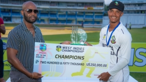CWI President Dr Kishore Shallow (left) presents the symbolic cheque to Guyana&#039;s Tevin Imlach
